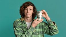 A teenager holds a jar full of $100 bills.