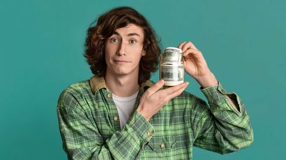 A teenager holds a jar full of $100 bills.