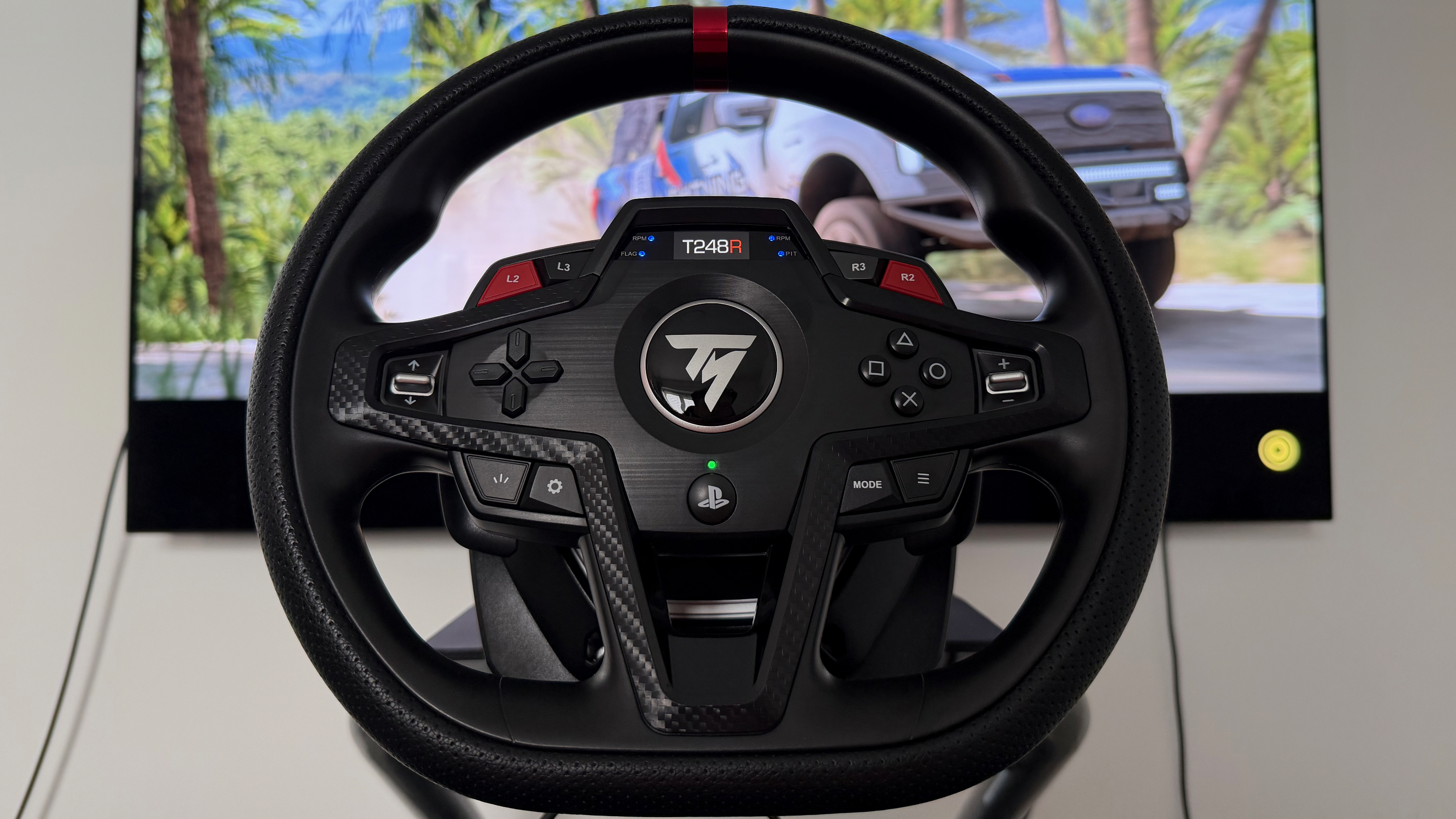 A Thrustmaster T248R in front of a gaming screen playing Forza Horizon 5