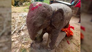 We see the elephant statue with a red mark mark on its head and a red cloth tied around its back foot.