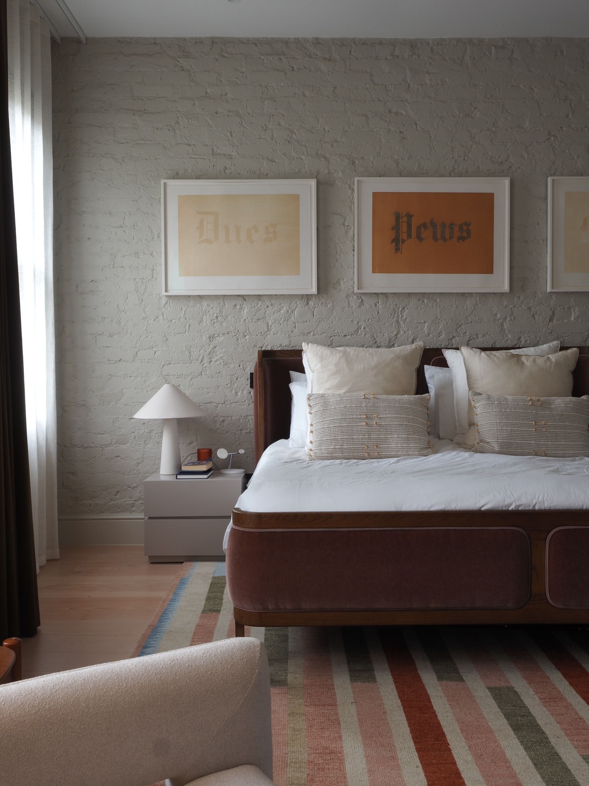 a bedroom with a white brick walk, art on the wall, and a striped rug