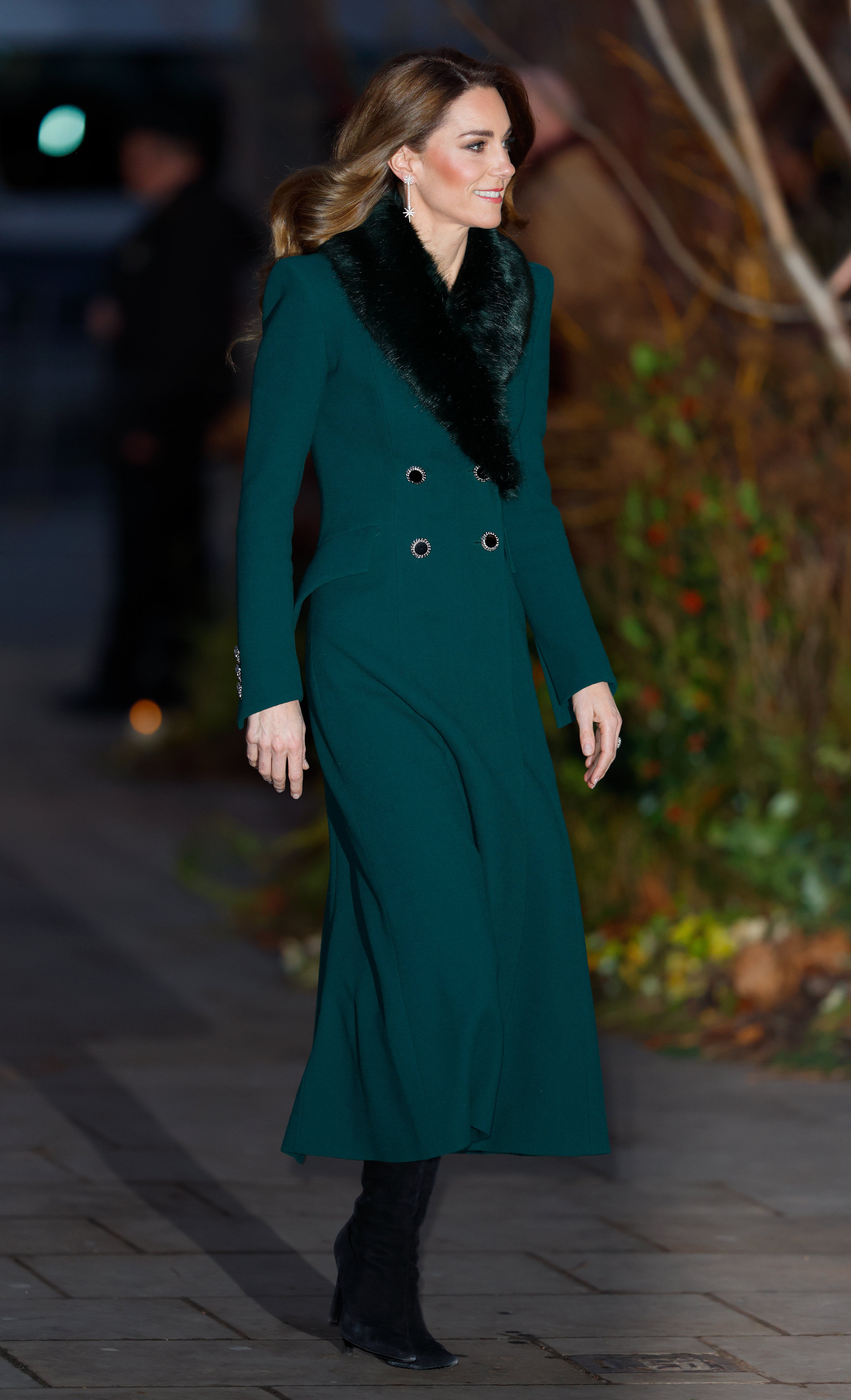 Princess Kate walking outside wearing a green coat and fur scarf at the Together at Christmas concert 2025