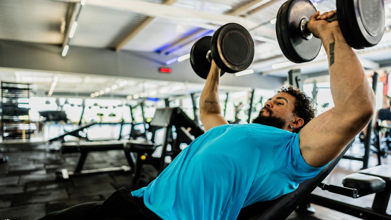 A man performing incline dumbbell press as part of his workout