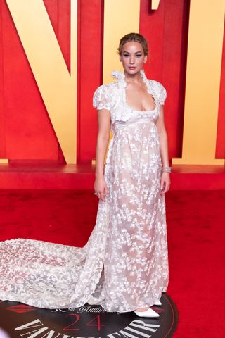 Jennifer Lawrence na festa pós-Oscar da Vanity Fair em 2024 usando um vestido branco da Givenchy e salto gatinho Manolo Blahnik.