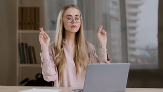 girl using laptop hoping for good luck with her fingers crossed