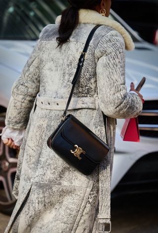 a photo of a woman wearing a gray coat with a celine designer bag
