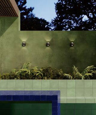 Modern backyard with green tiling, and green walls with trio of linear minimalist wall lights.