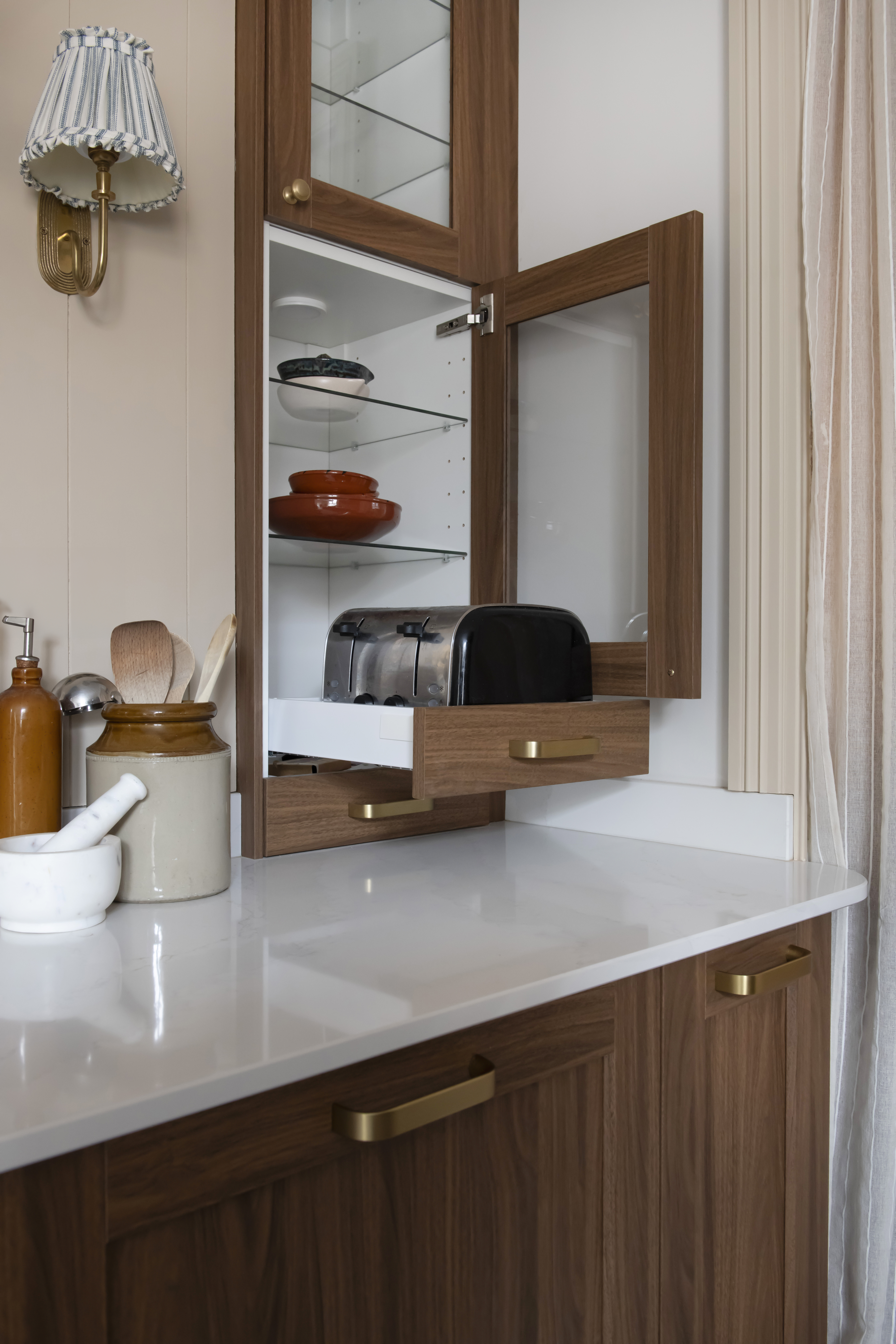 toaster within a drawer in a kitchen cupboard above a cabinet with white countertops and brown wood cupboard drawers