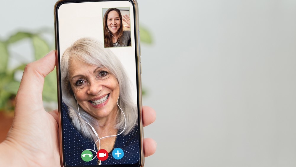 A video call between two women is shown on a smartphone.