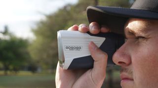 The Gogogo LockedIn Rangefinder is held by a golfer