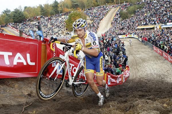 Bart Wellens runs uphill. A huge crowd is visible in the background.