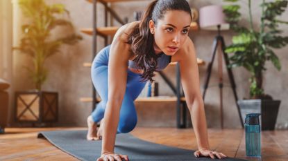 A woman performing mountain climbers on a yoga mat during a home workout