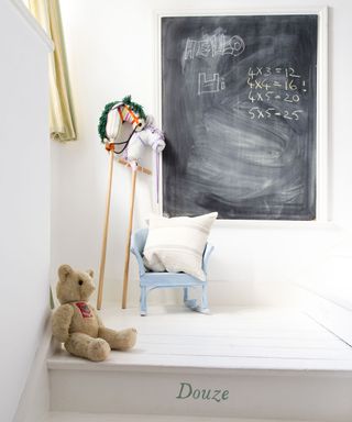 childs room with teddy bear and blackboard on wall