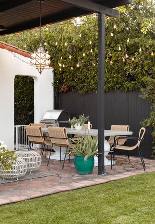 Patio space with outdoor furniture, black fence and greenery with mixture of fairy lights and lanterns