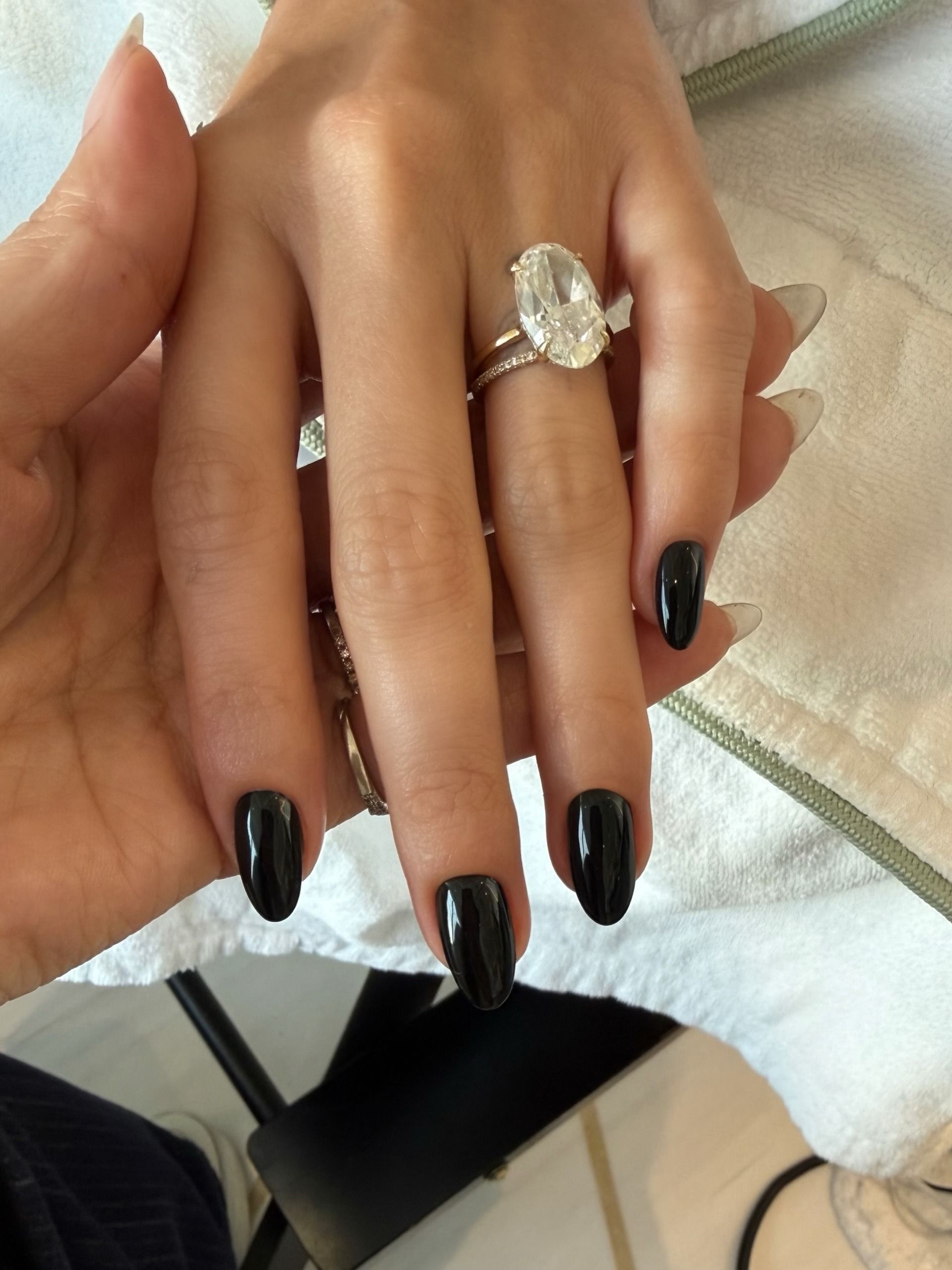 glossy black almond nails on hailey bieber hands with a big diamond ring