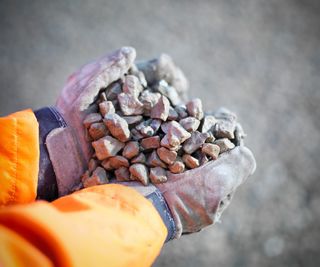 Gloved hands holding crushed stones in quarry site