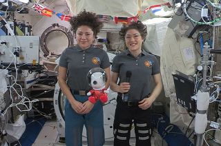 Expedition 61 crewmates Jessica Meir (left) and Christina Koch of NASA reveal an Astronaut Snoopy doll on the International Space Station during the 2019 Macy&#039;s Thanksgiving Day Parade. 