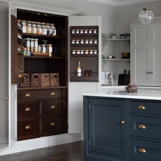 Kitchen with dark blue-green island and wooden built in pantry cupboard