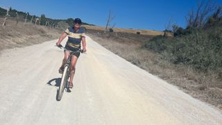 A smiling woman riding a shopping bike on dirt road
