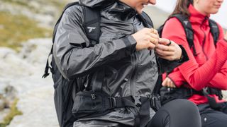 A hiker adjusts the straps on her backpack