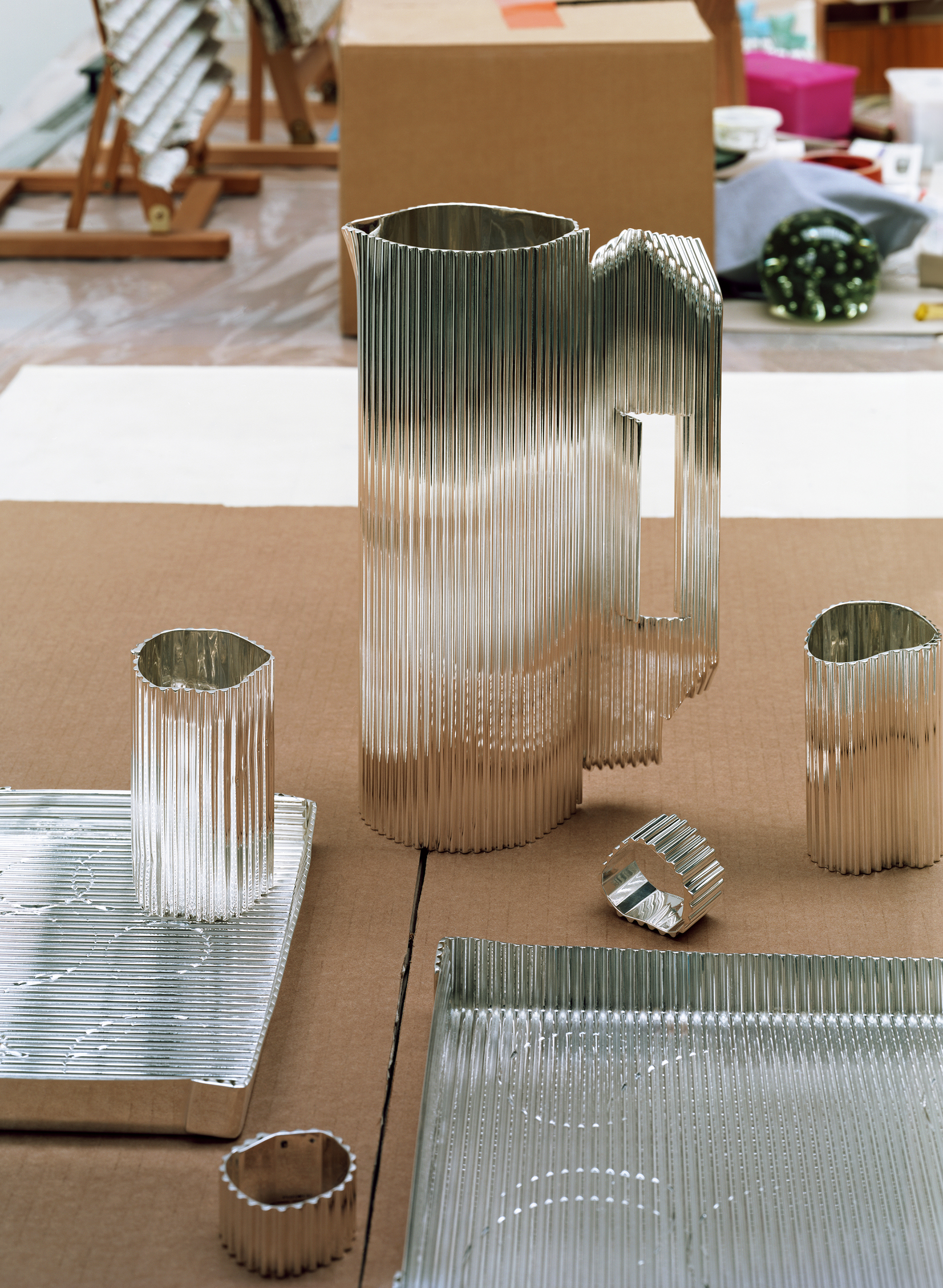Silver objects with a ridged surface, shown in the context of a messy artist&#039;s studio