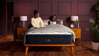 A couple talk and laugh while sat on the DreamCloud Premier Mattress