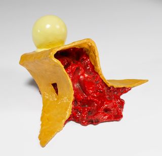 A yellow sculpture has a gooey red interior