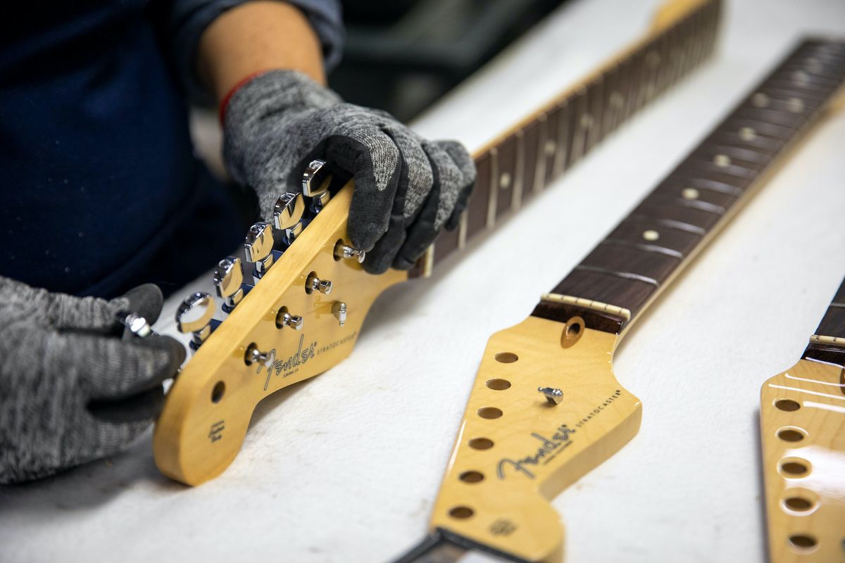 A technician works on a guitar's headstock at Fender's Mod Shop