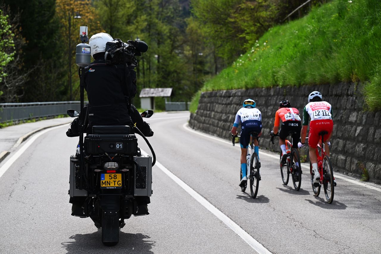 A camera bike follows three cyclists at a race
