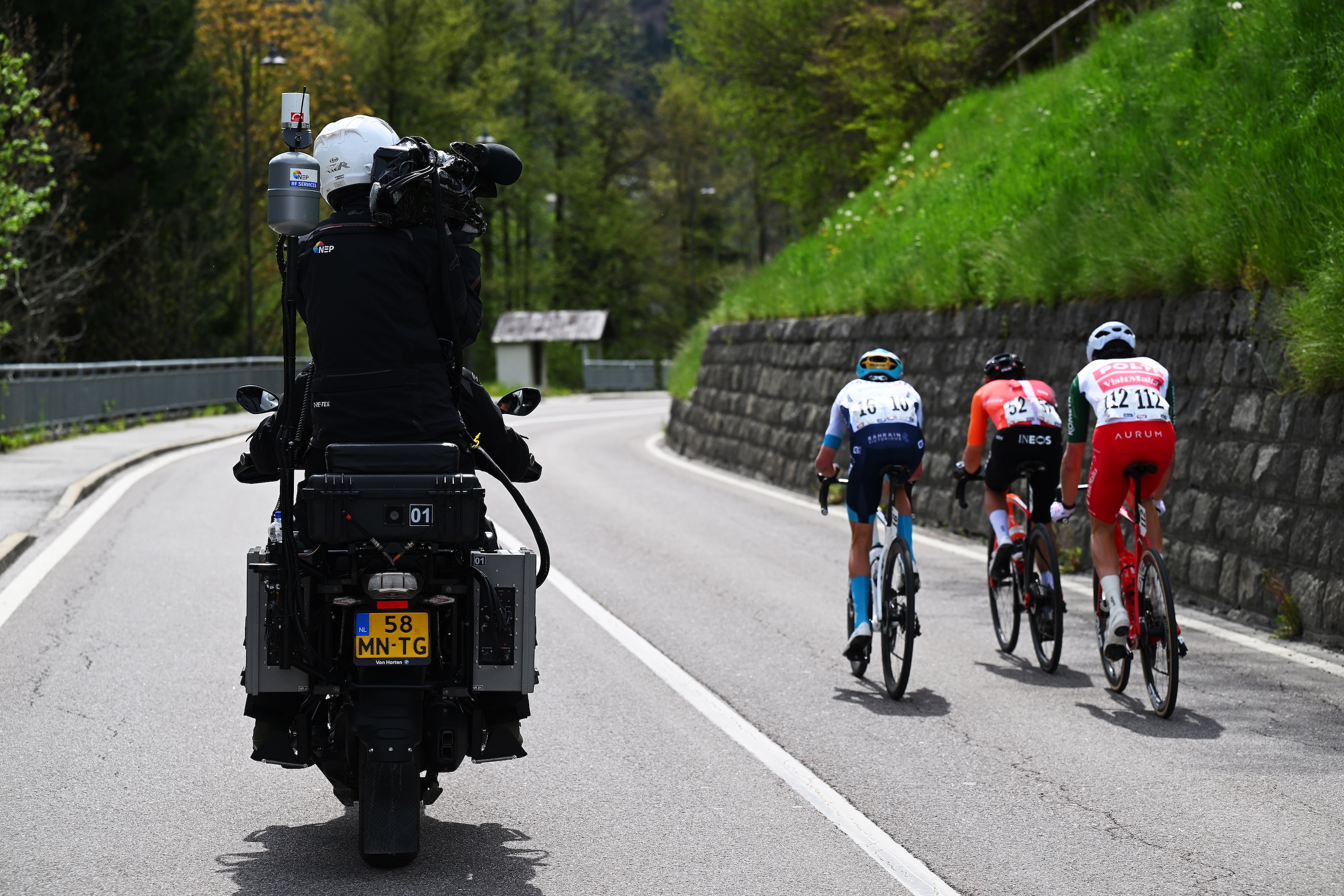 A camera bike follows three cyclists at a race