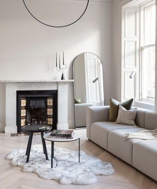 renovating living room decorated in off white with cream sofas, large windows and tiled fireplace