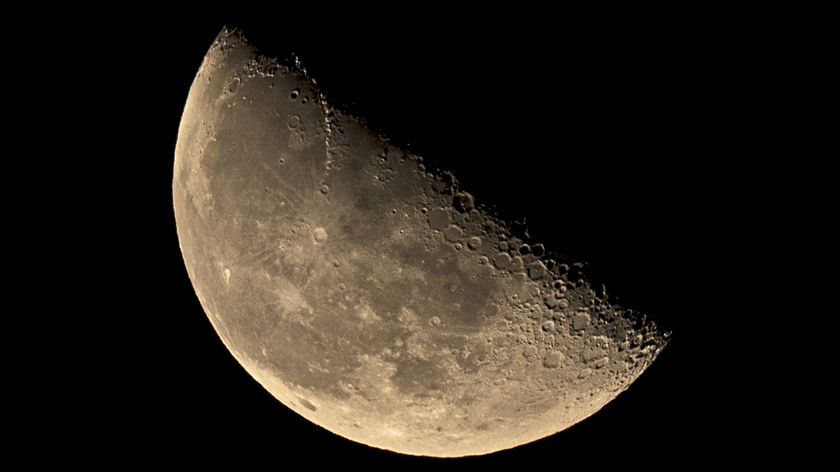 close up view of the third quarter moon, appears half illuminated with large craters peppering the surface. 