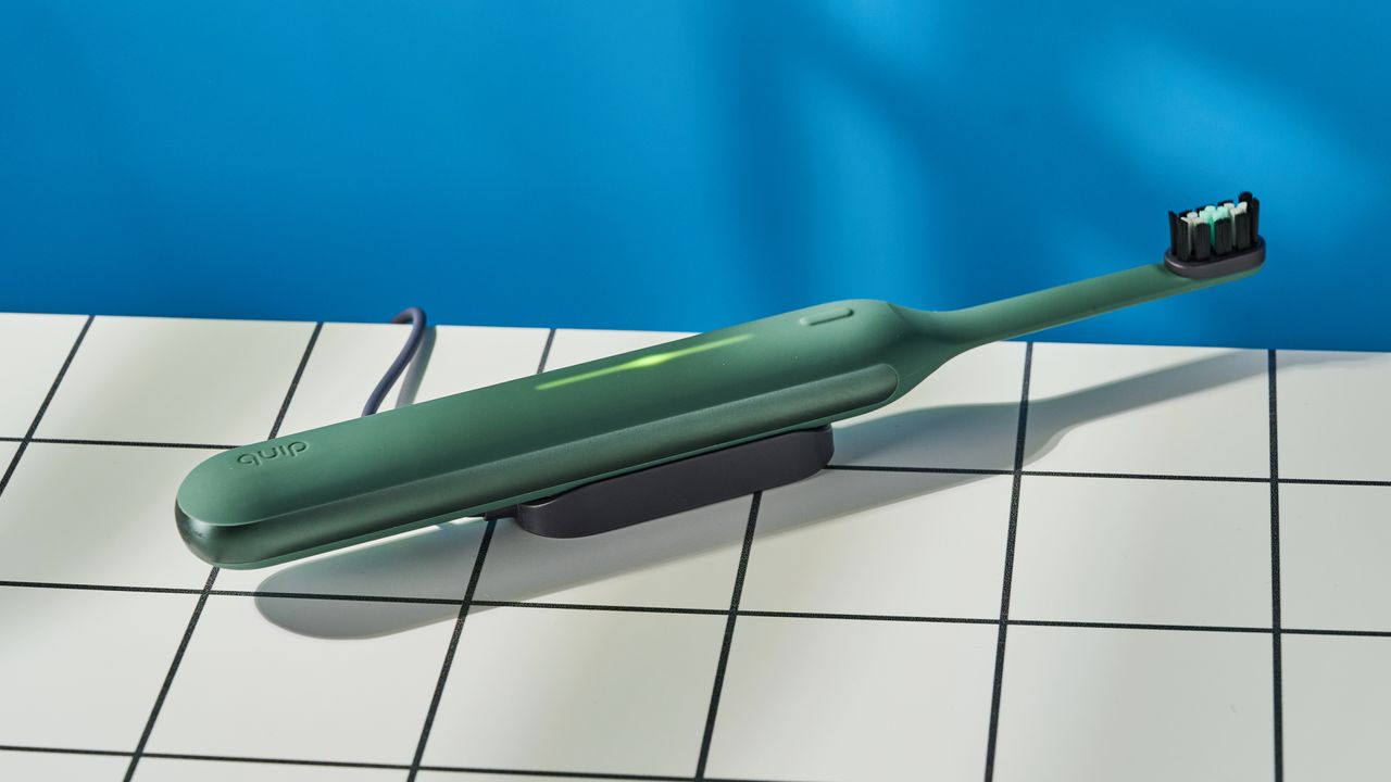 Quip Ultra Next Generation Smart Sonic Electric Toothbrush photographed in front of a blue background.
