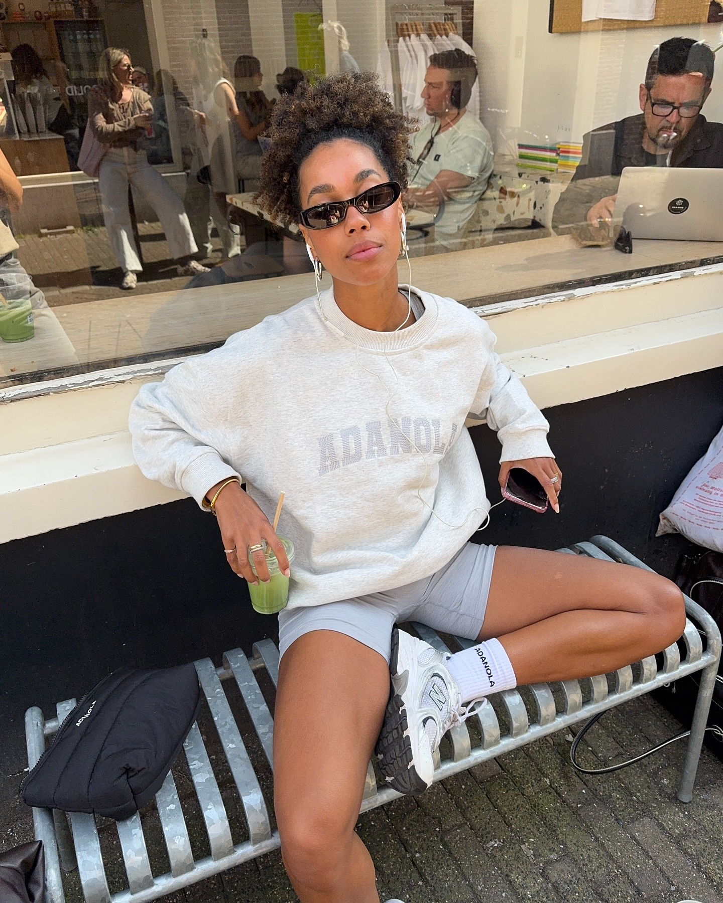 A woman sitting outside a coffee shop in gym gear with a high ponytail hairstyle