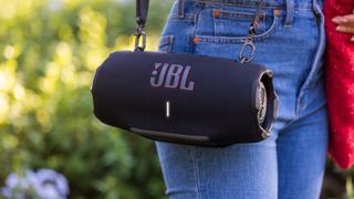 JBL Xtreme 4 in black with person carrying it using the strap
