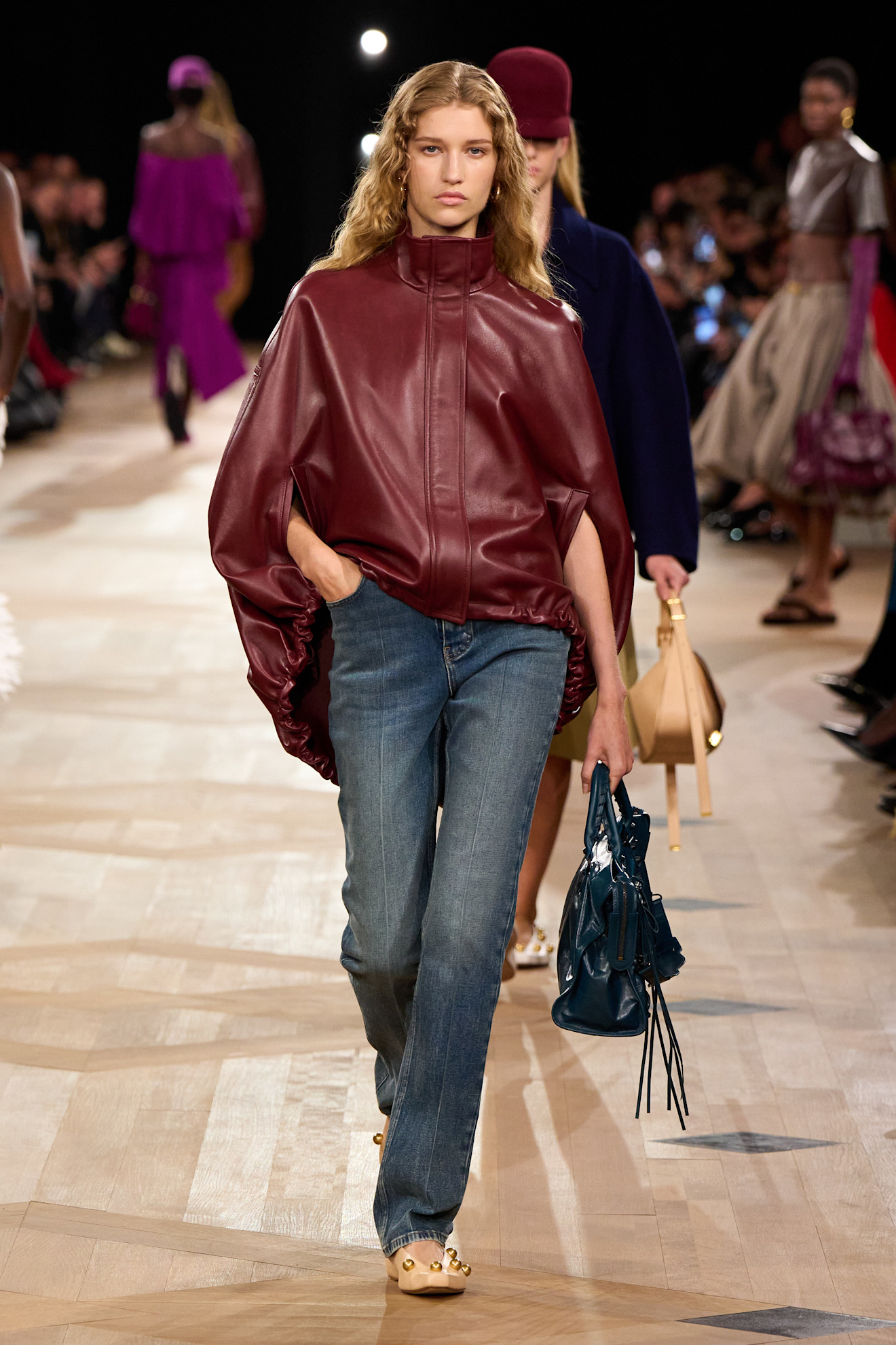 a woman wearing blue cigarette jeans and a red leather jacket on Balenciaga Spring 2026 runway