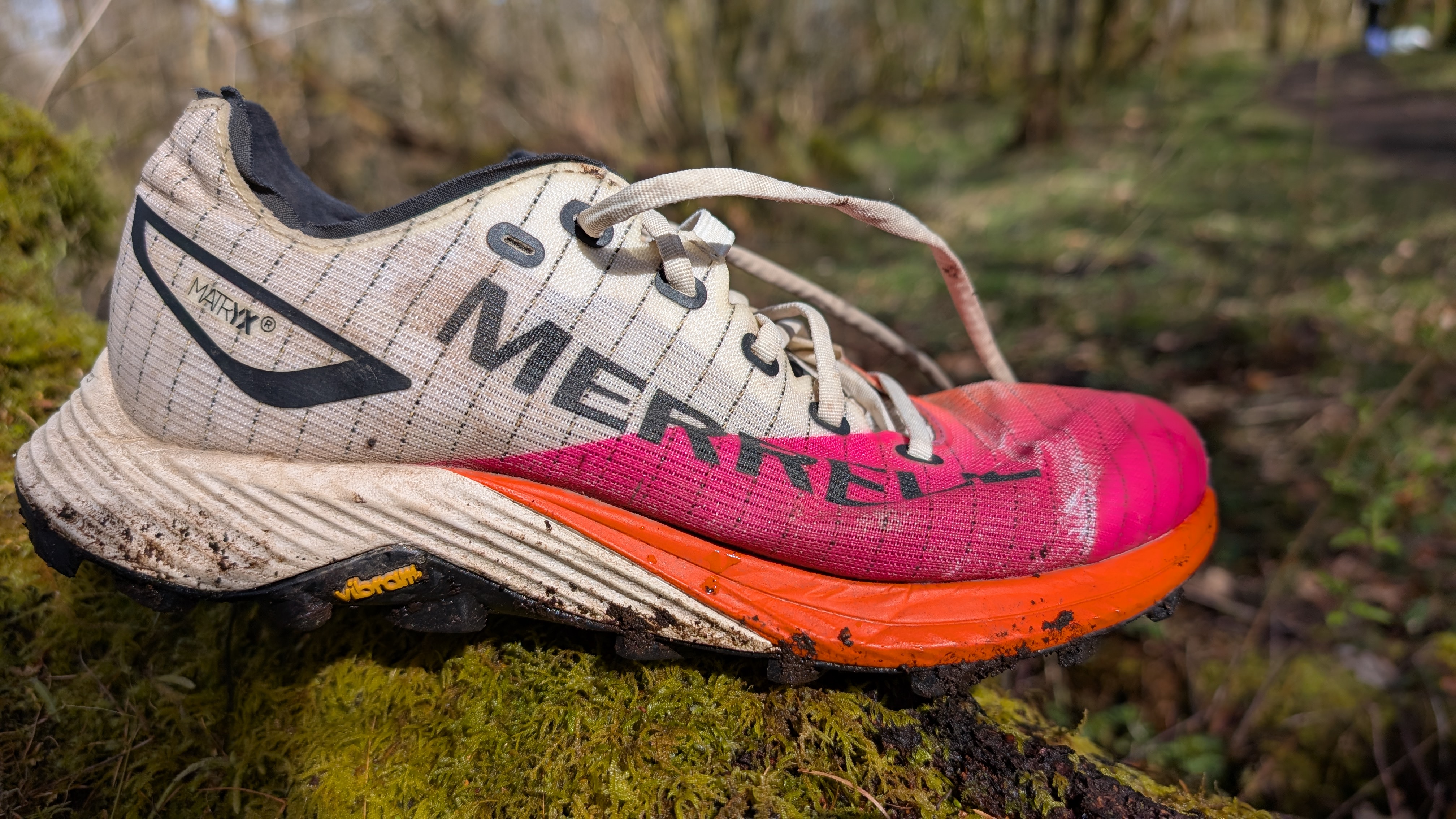 The Merrell MTL Long Sky 2 trail running shoe in pink and ornage in the forest