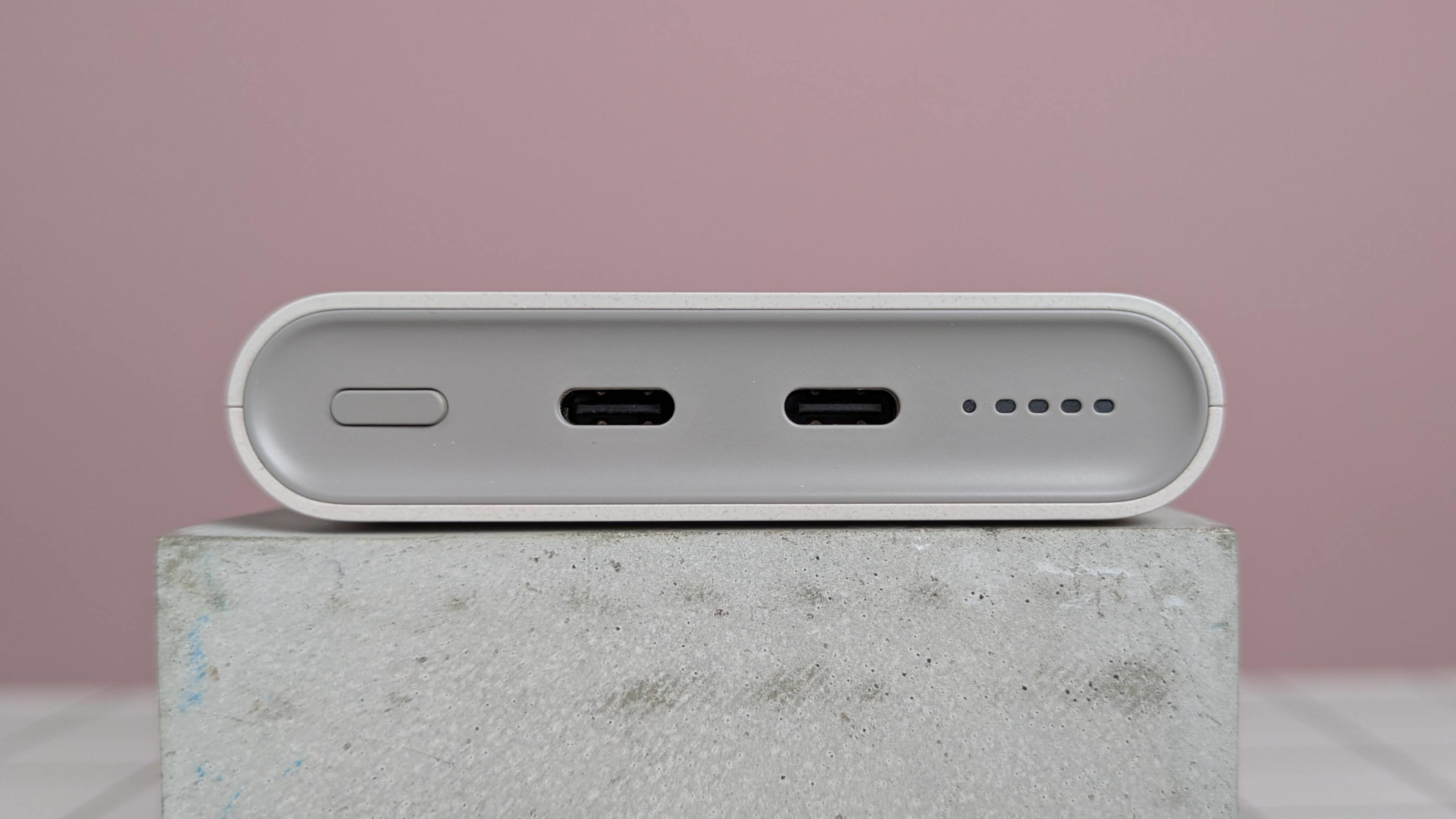 Close-up of ports on Samsung 25W 10,000mAh Wireless Battery Pack, on plinth on desk with pink background