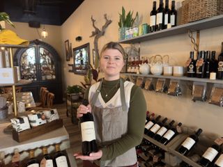 Regan Schneider holds a bottle of wine inside her store Corbeaux Wine & Tea House in Temecula, California
