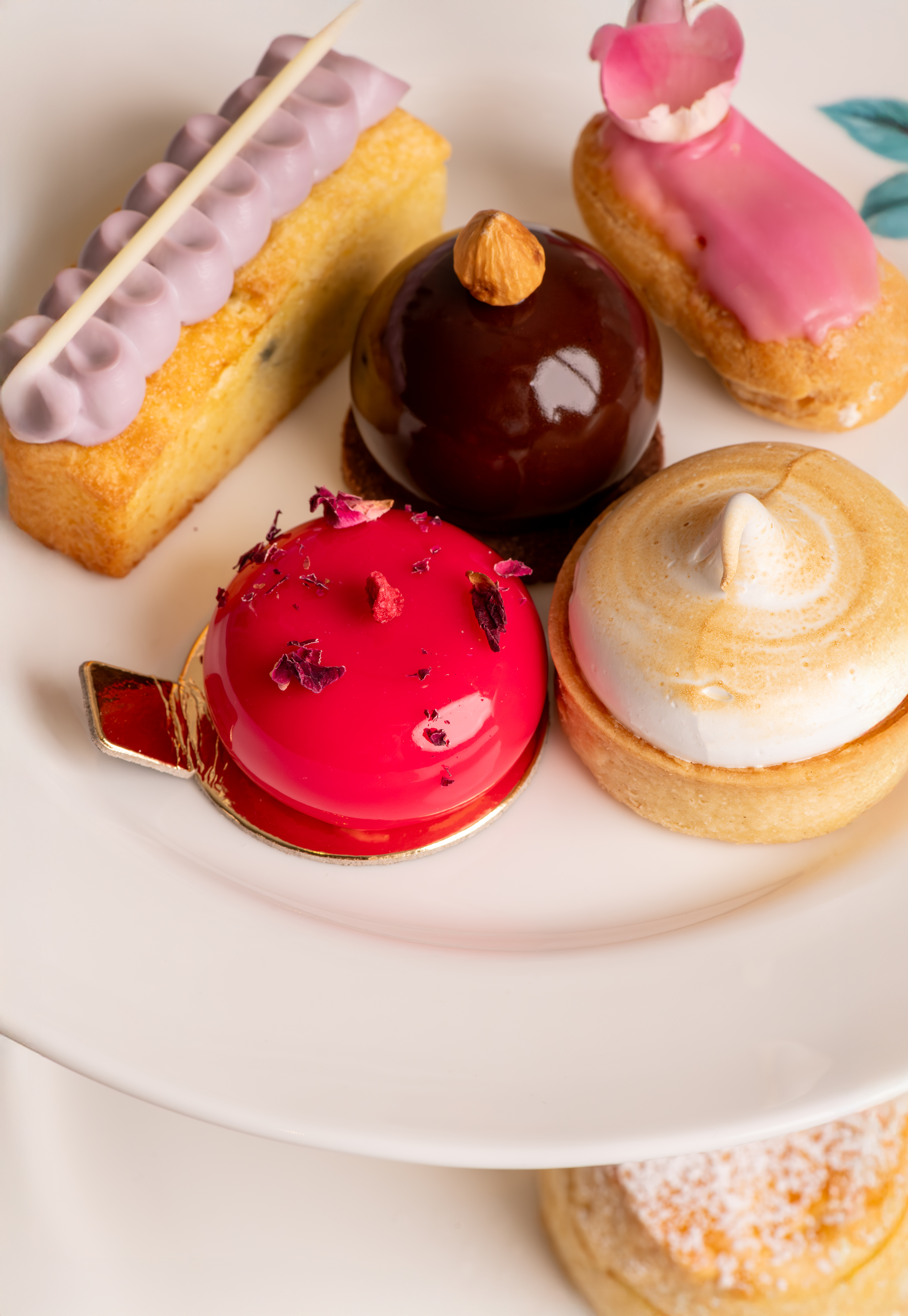 A series of high-end pastries sits in a white ceramic dish decorated in different, bright glazes.