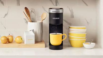Keurig coffee maker on countertop with yellow mug and yellow accessories