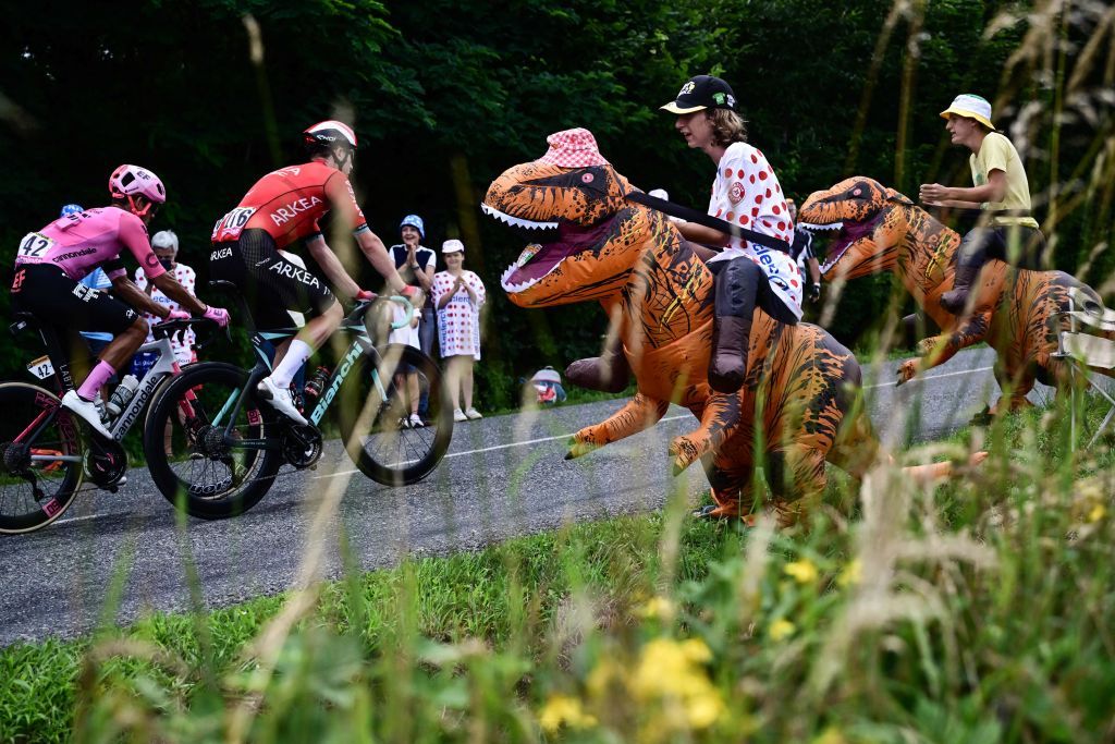 Spectators wearing inflatable dinosaur costumes cheer along the race route as a breakaway cycles past during the 11th stage of the 110th edition of the Tour de France cycling race 180 km between ClermontFerrand and Moulins in central France on July 12 2023 Photo by Marco BERTORELLO AFP Photo by MARCO BERTORELLOAFP via Getty Images