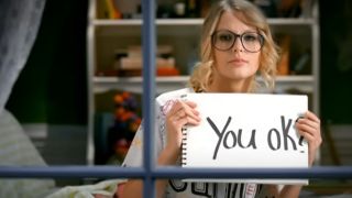 Taylor Swift holding up a sign that says "You OK?" in the You Belong with Me music video.