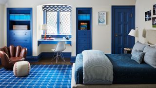 A child's bedroom with white wall, blue painted accents and a chair shaped like a baseball mit