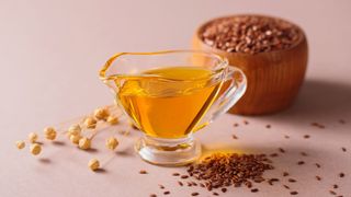 Flaxseed oil in glass jug with bowl of flaxseeds next to it