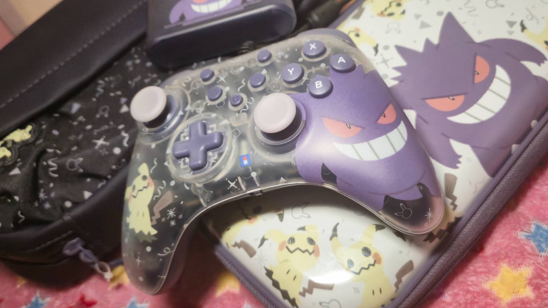 Photo of a pile of official Switch 2 Hori Gengar and Mimikyu accessories sitting on a pink blanket.