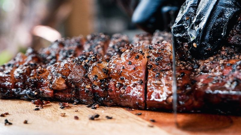 person cutting into smoked meat