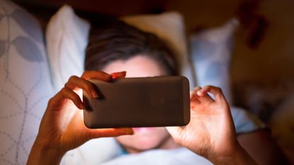 Woman addicted to tracker in bed reading phone night time