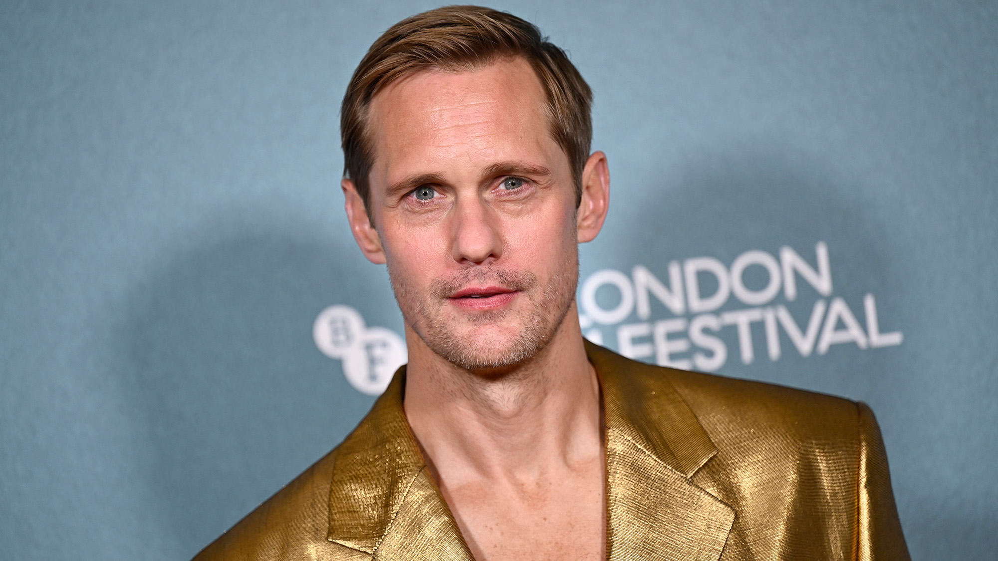 Alexander Skarsgard in a gold suit at the 2026 London BFI Wicker premiere. 