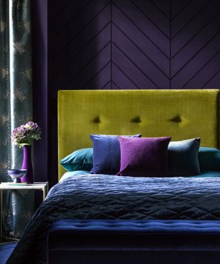 bedroom with deep purple walls, ochre headboard and purple bedding
